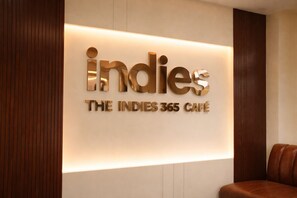 Eine Wand mit einem Schild für 'Indies The Indies 365 Café' mit einem modernen, beleuchteten Design.