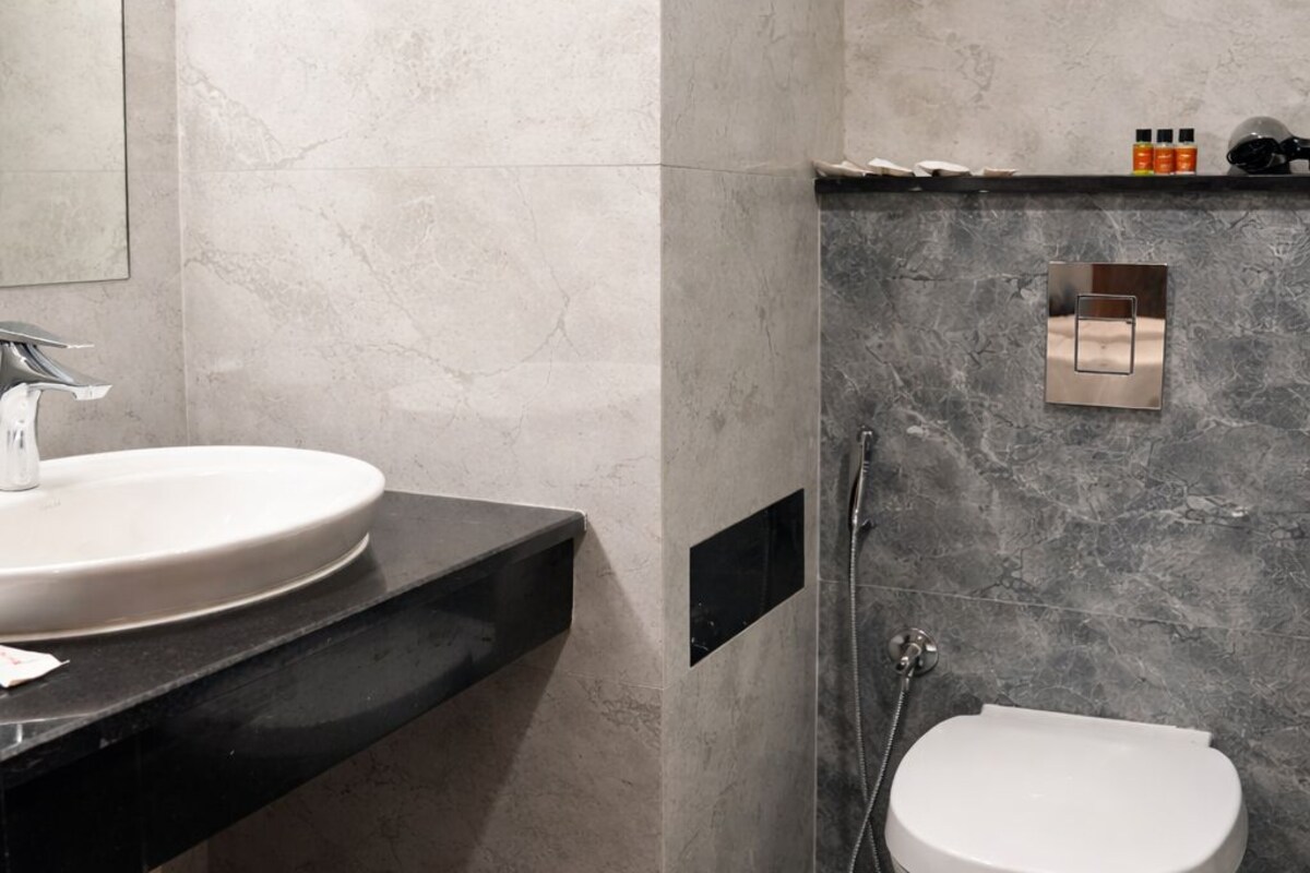 Un baño moderno con un lavamanos blanco, inodoro y zona de ducha.