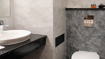 Un baño moderno con un lavamanos blanco, inodoro y zona de ducha.