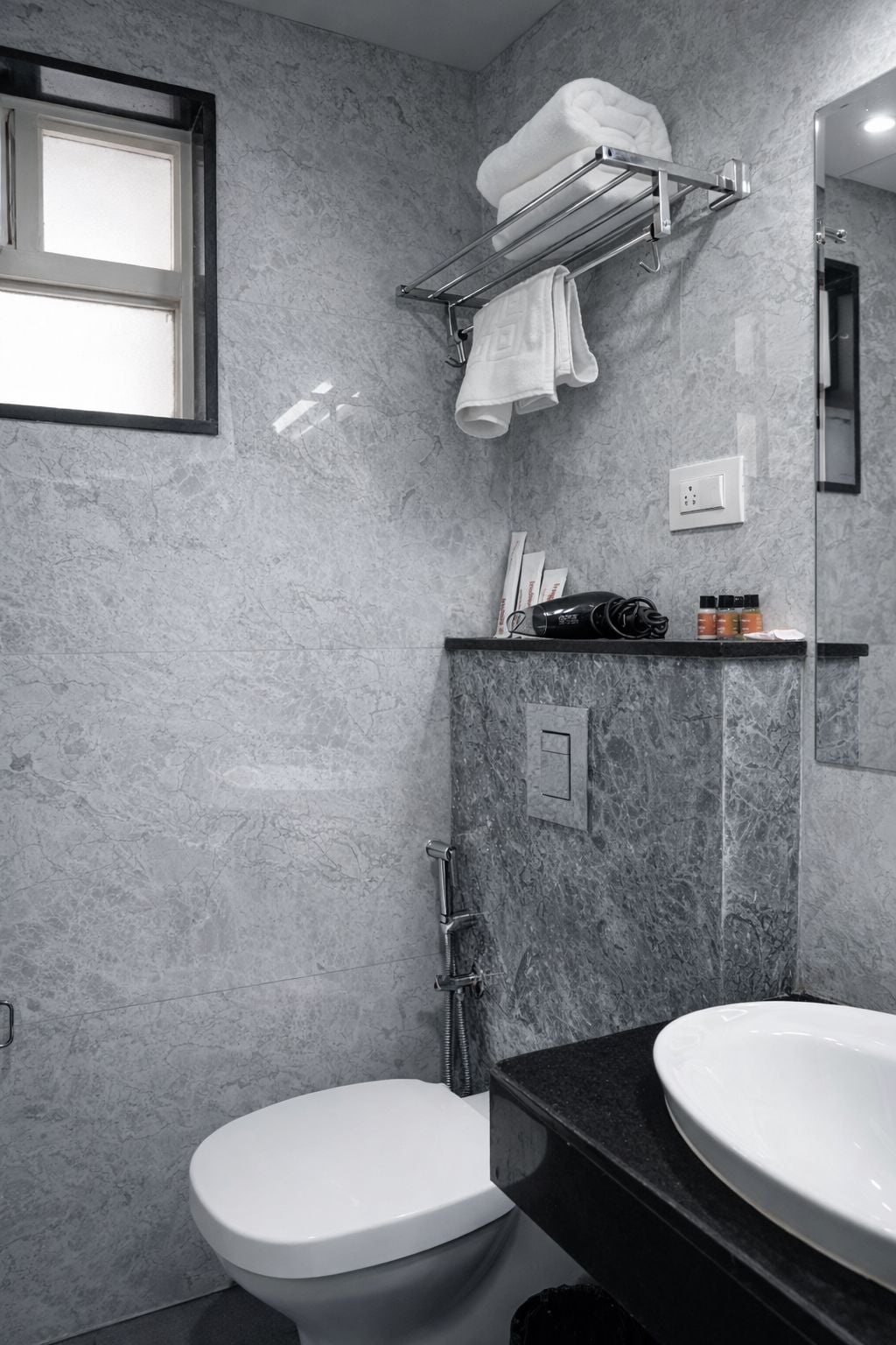 A bathroom with a toilet, a sink, a towel rack, and a shower.