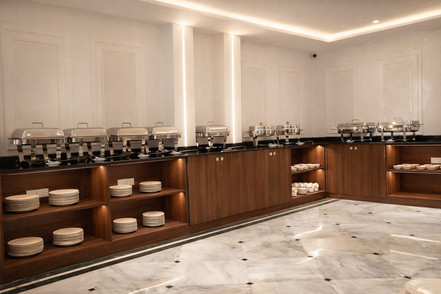 Una cocina moderna con electrodomésticos integrados, armarios de madera y suelo de mármol.
