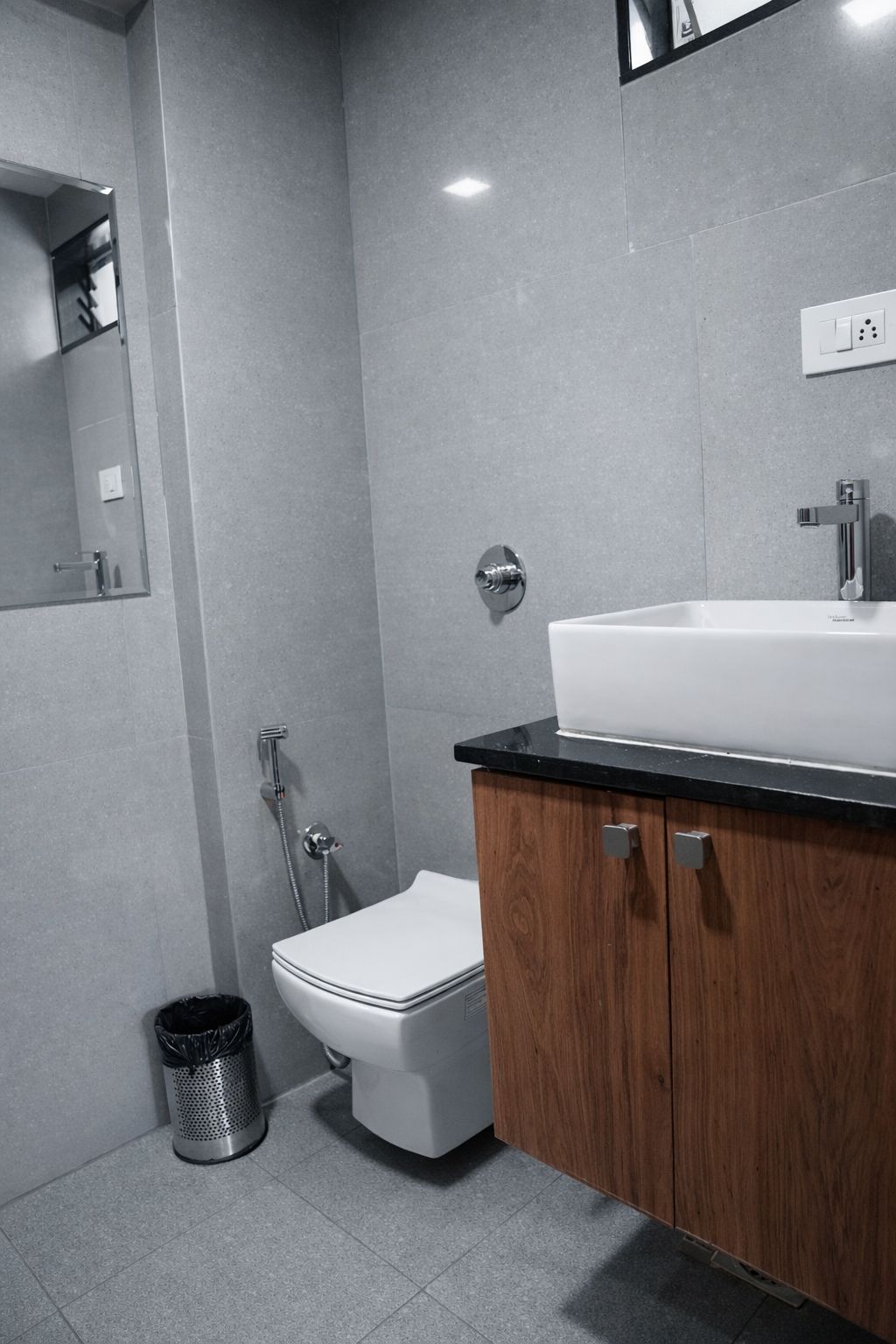 A modern bathroom with a white toilet, a wooden cabinet with a sink, and a shower area.