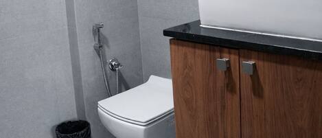 A modern bathroom with a white toilet, a wooden cabinet with a sink, and a shower area.