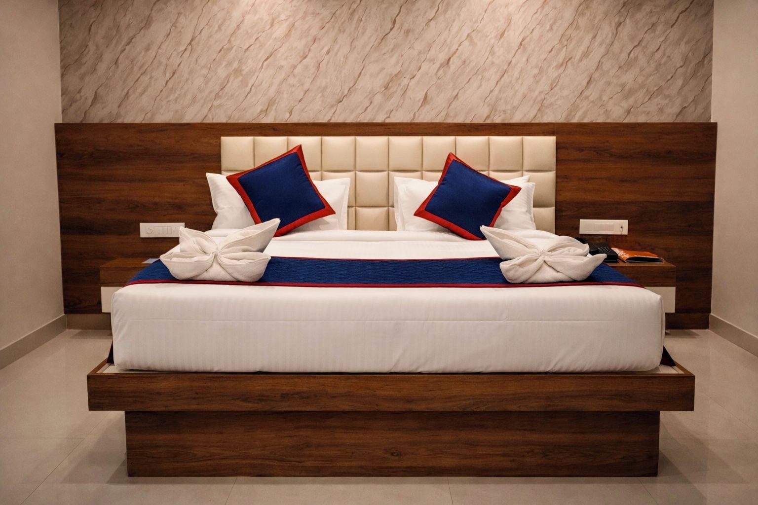 Habitación de hotel moderna con una cama grande, cabecero de madera y pared con diseño de mármol.
