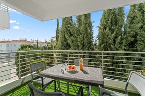 Ein Balkon mit Tisch, Stühlen und einer Fanta-Flasche.