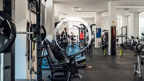 A gym with exercise equipment, a weight bench, and a treadmill. - Cosy 2Br Family Apartment - Mythical Sands Resort (Paralimni)