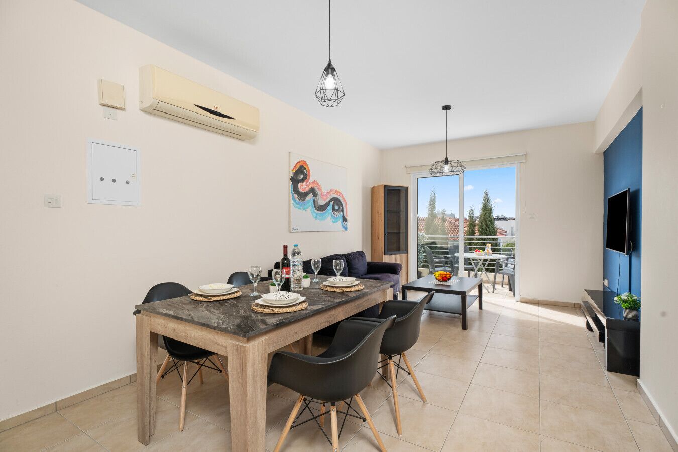 En moderne lejlighed med spiseplads, opholdsstue og balkon med udsigt over byen.