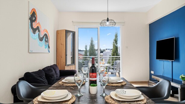 Een eetruimte met een tafel voor vier personen, een fles wijn en uitzicht door een glazen deur.