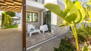 A modern building with a covered patio, outdoor seating, and lush greenery. - Stylish Villa | Private Pool - Garden - Near Beach (Paralimni)