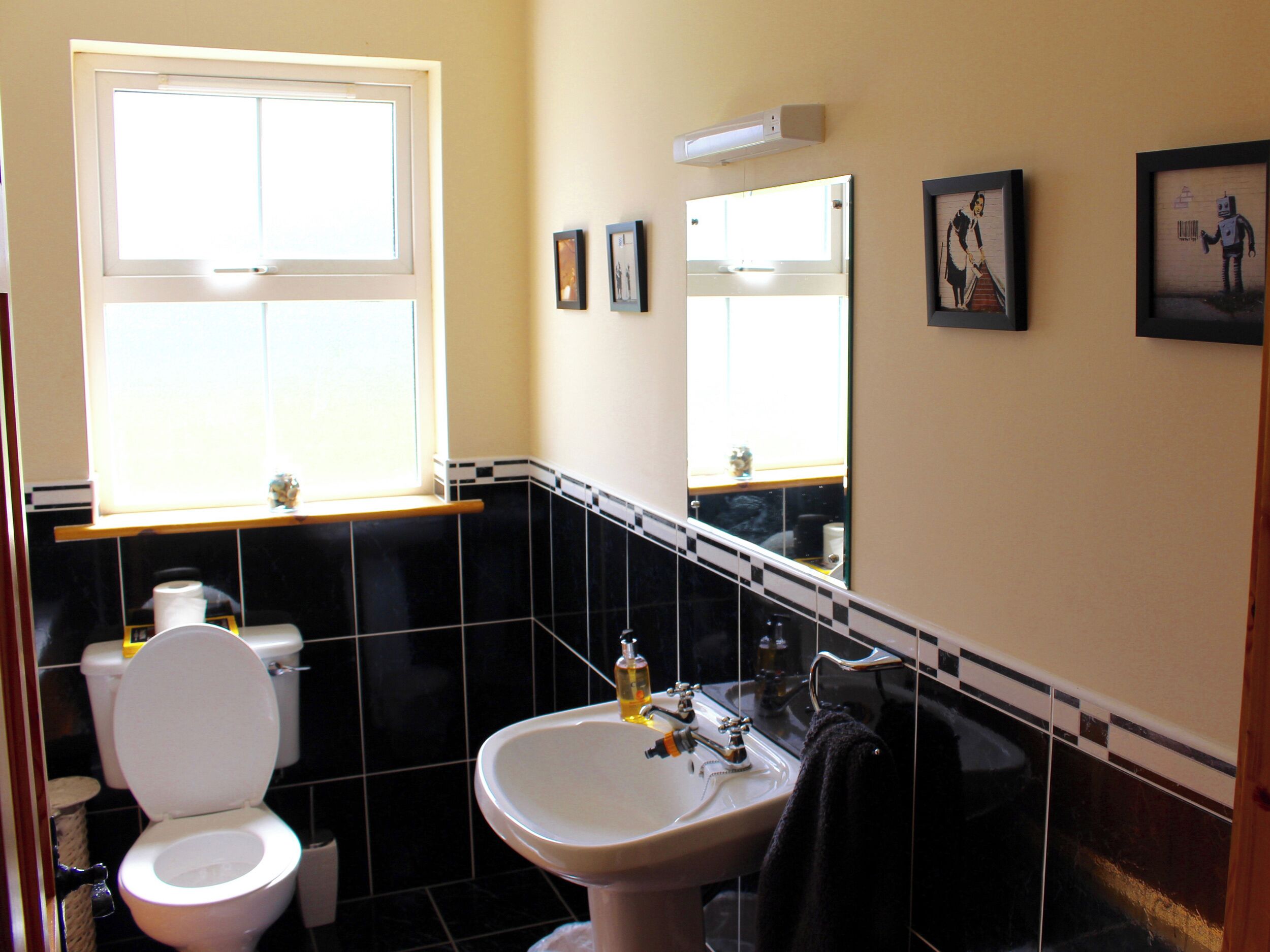 A bathroom with a toilet, sink, and mirror.