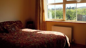 Ein Schlafzimmer mit einem großen Bett, einem Fenster mit Blick auf Grünflächen und einer Heizung.