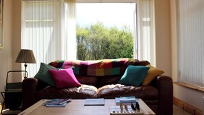 Ein Wohnzimmer mit einem braunen Ledersofa, einer bunten Decke und einem Holztisch.