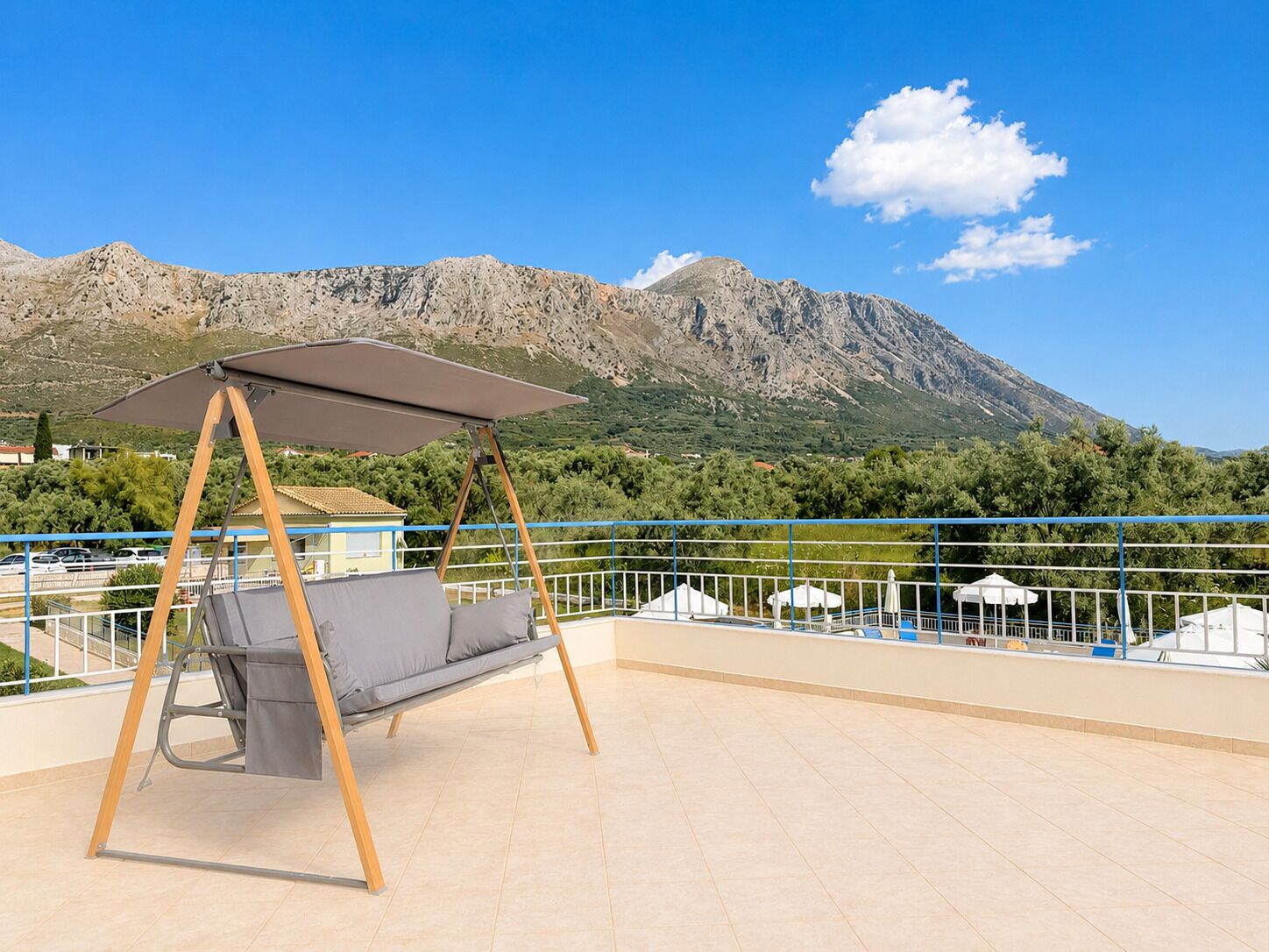 A terrace with a swing chair, a view of mountains, and a railing.