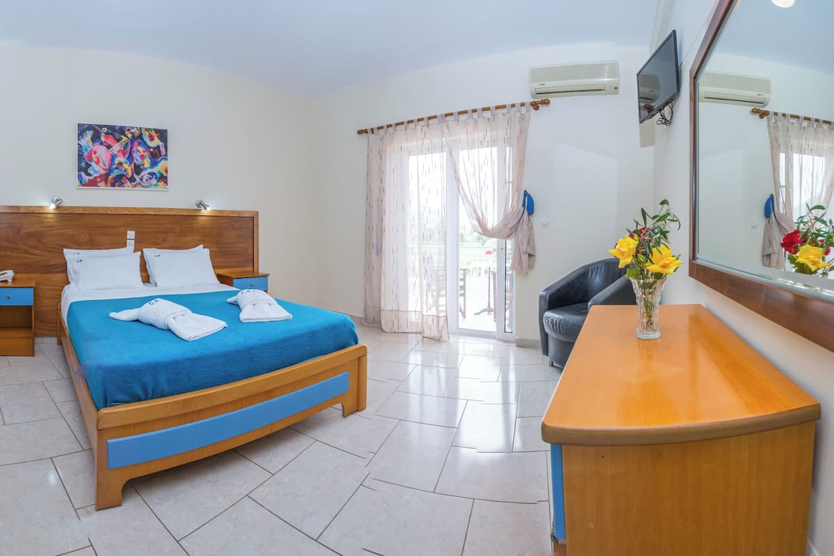 A hotel room with two beds, a desk, a TV, and a bathroom visible through the window.