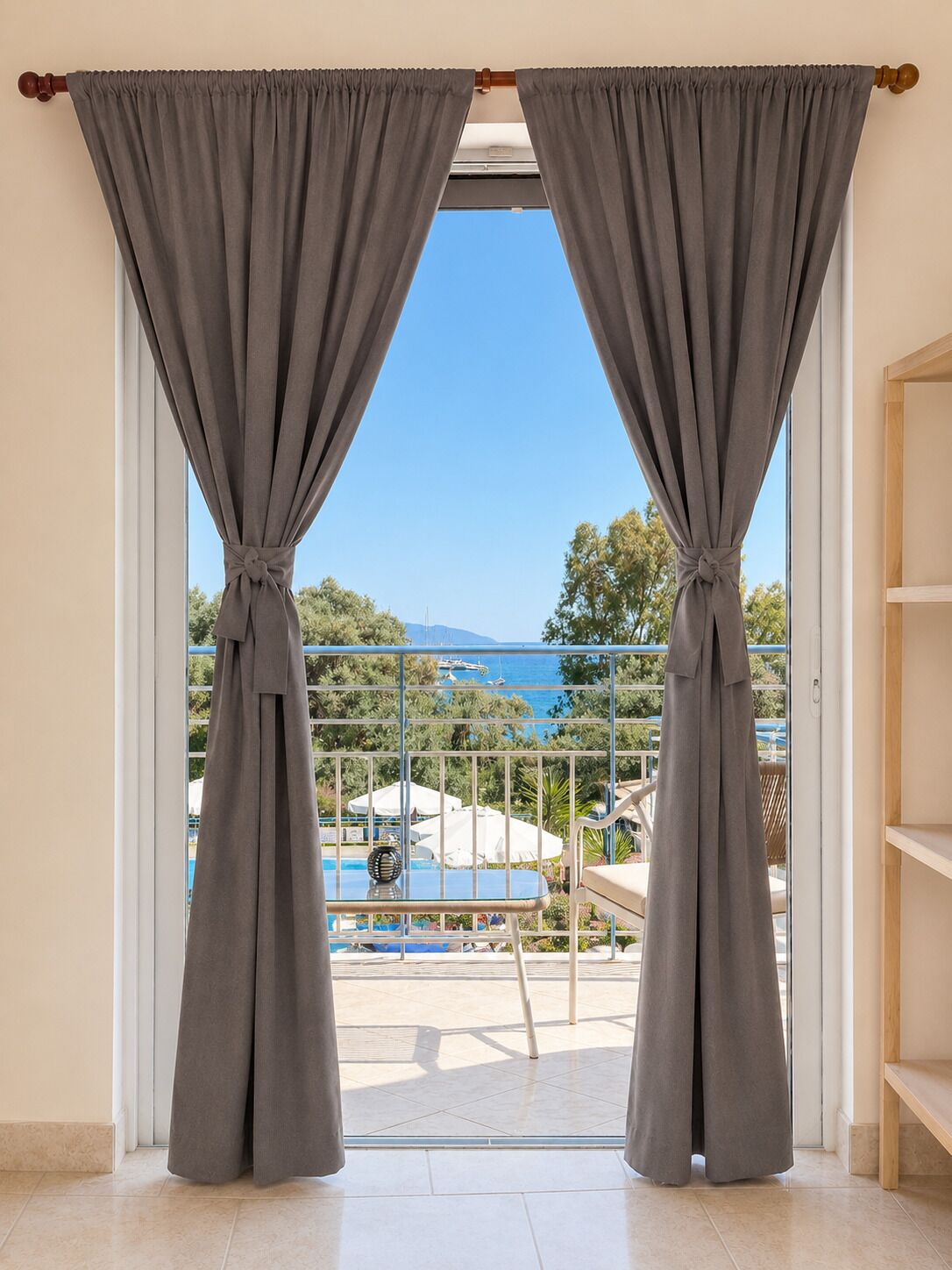 A room with a view of a pool and outdoor furniture, a wooden door, and a tiled floor.