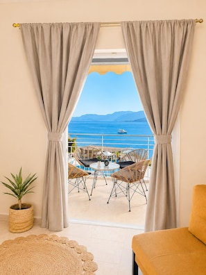 A balcony with wicker furniture, a potted plant, and a view of the sea.