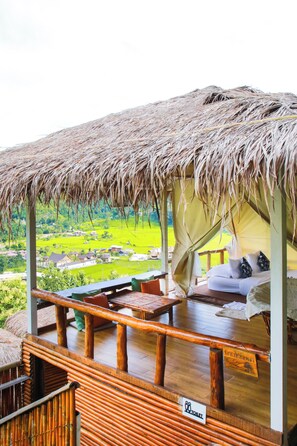 A thatched-roof outdoor seating area with a view of a green landscape. - SAIMOK Bokrak NAN (Bo Kluea)