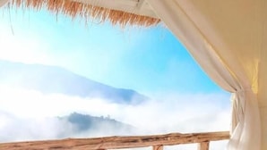 Une personne allongée sur un lit, avec vue sur une rivière et des montagnes.