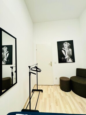 A room with a mirror, two framed pictures, a door, a small stool, and a sofa. - Bright 4BR Apt for 8 Near FAC Platz (Vienna)