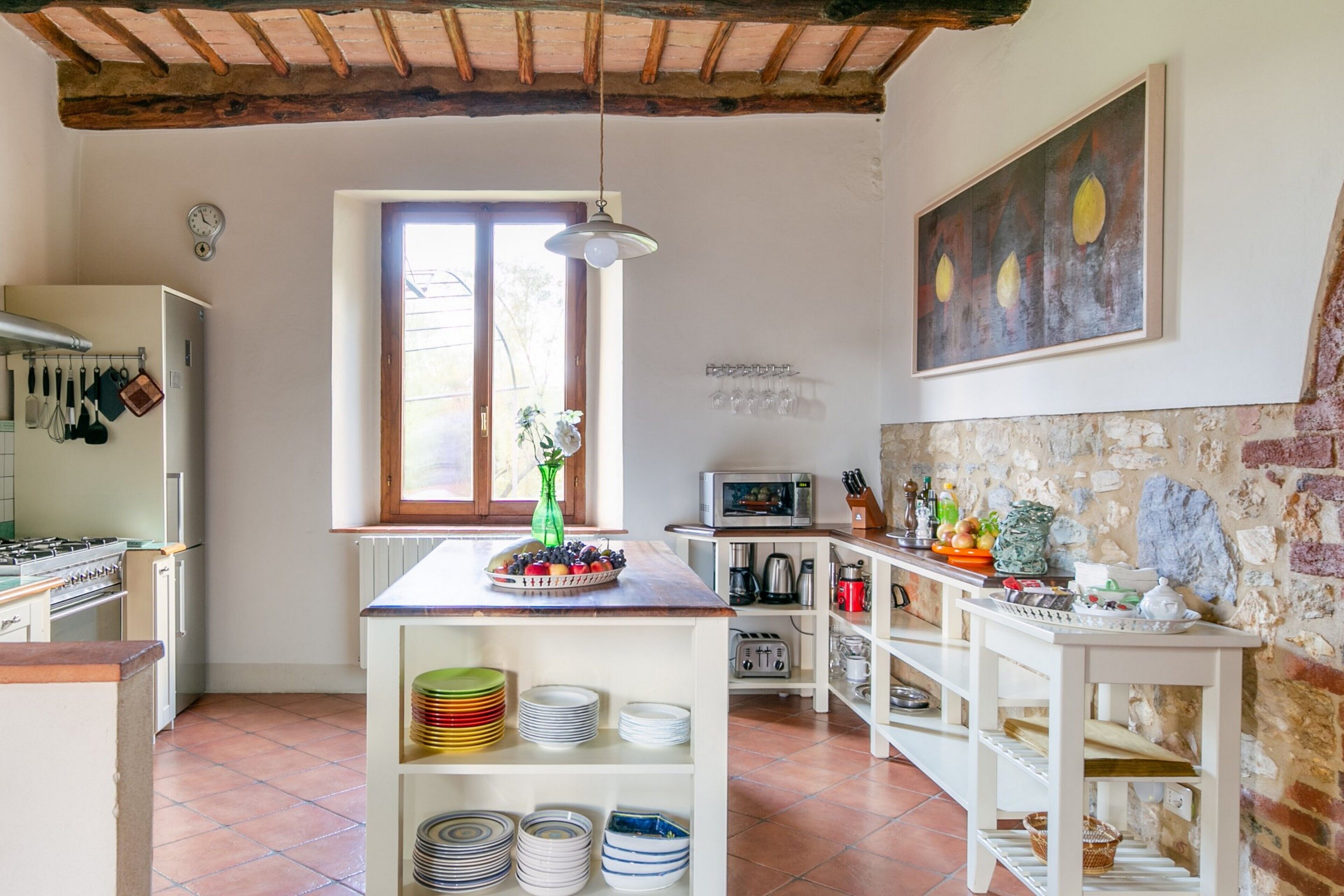 A kitchen with a rustic ceiling, a window with a view, and a variety of kitchen appliances and utensils.