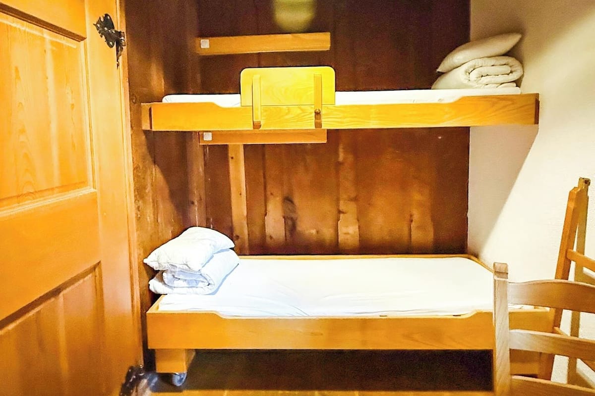Habitación con literas, paredes y piso de madera.