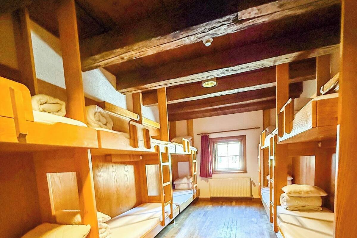 Varias literas en una habitación con suelo de madera y una ventana.