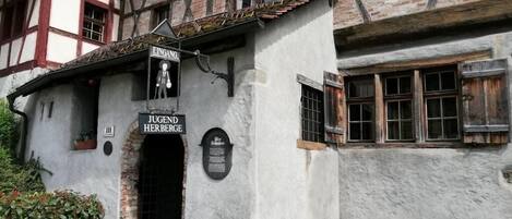 A traditional half-timbered building with a sign for 'JUGEND HERBERGE' and a small entrance.