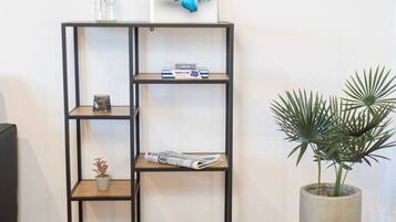 A black metal bookshelf with a blue butterfly artwork on top, a small potted plant, and a magazine on the middle shelf.