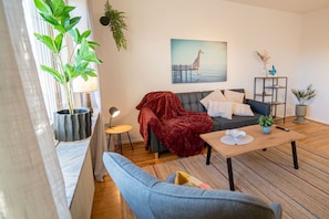 A living room with a sofa, a coffee table, a chair, a plant, and a painting of a giraffe. - Scandi-Boho 1BR | Calm & Well-Connected Location (Gothenburg)