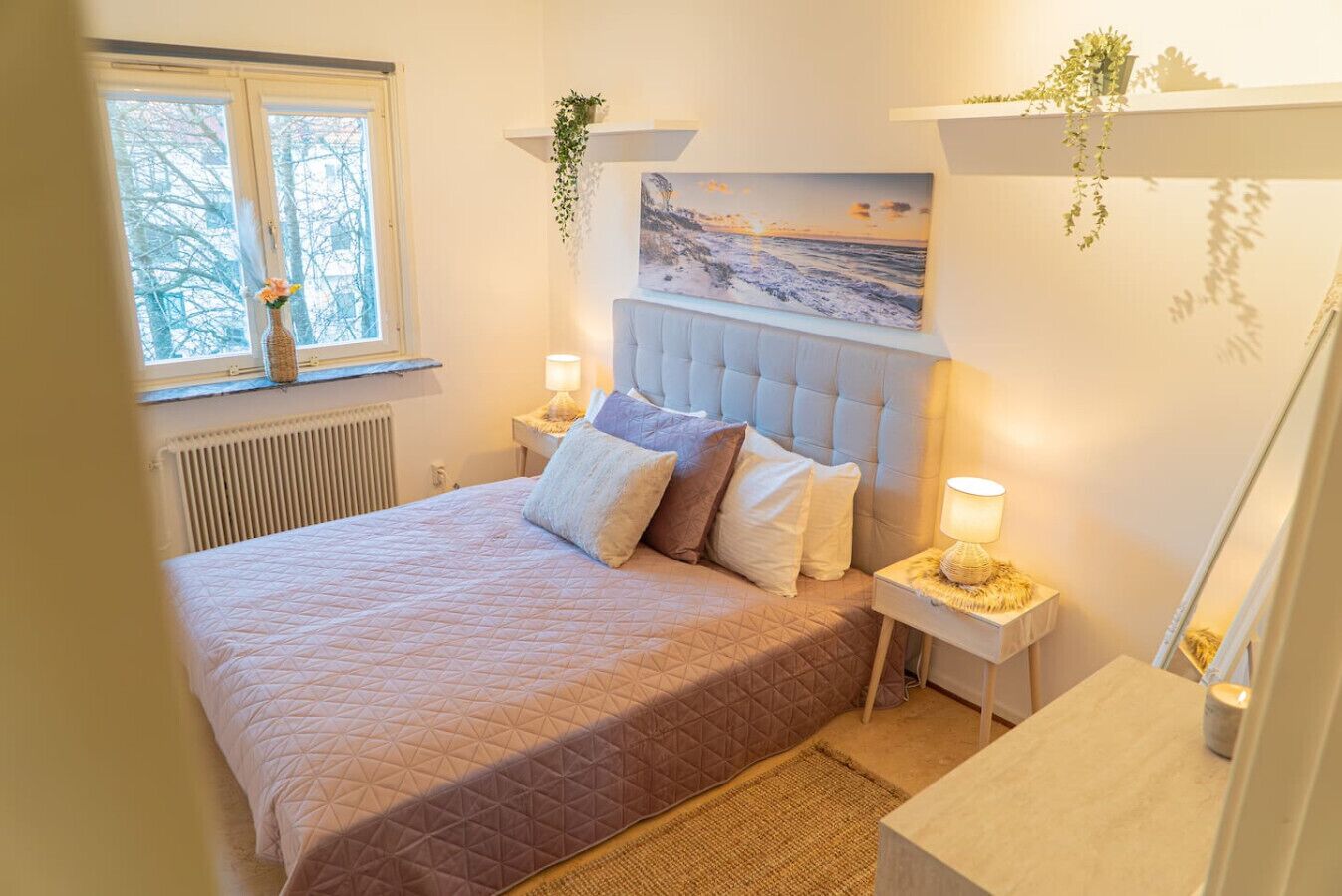 Une chambre à coucher avec un lit, des tables de chevet, une fenêtre et un tableau au mur.