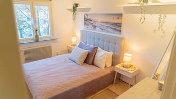 Une chambre à coucher avec un lit, des tables de chevet, une fenêtre et un tableau au mur.