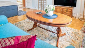 Un soggiorno con un tavolino rotondo in legno, un divano blu, una televisione e un quadro appeso al muro.