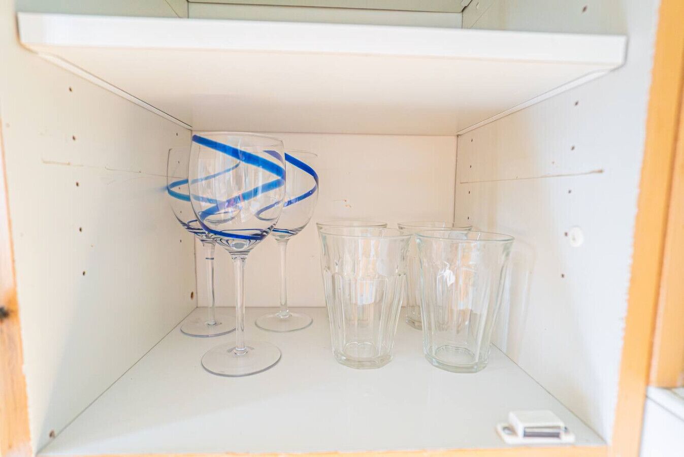 Uno scaffale bianco con tre oggetti di vetro trasparente, uno con decorazioni blu.
