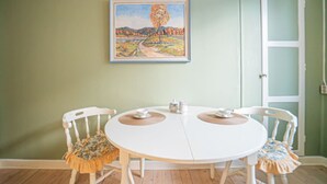 Un'area pranzo con un tavolo rotondo, due sedie, un quadro appeso e una porta.