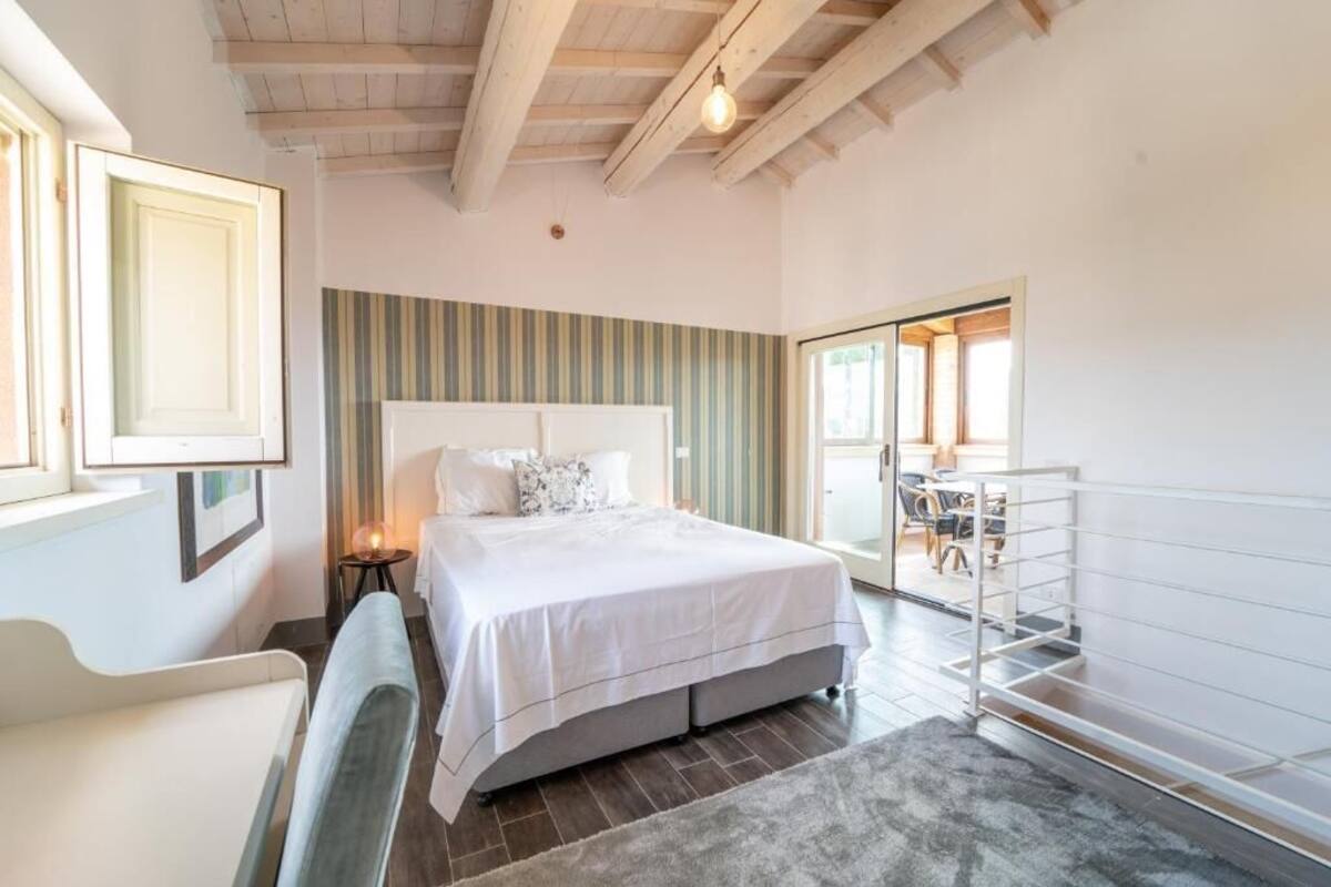 A bedroom with a bed, bedside table, and a view of the outside.