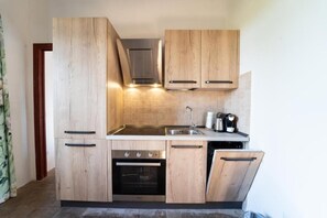 Una cocina moderna con armarios de madera, un lavamanos de acero inoxidable y un horno empotrado.