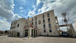 Un edificio storico con diverse bandiere, una facciata in pietra e un ingresso con cancello.