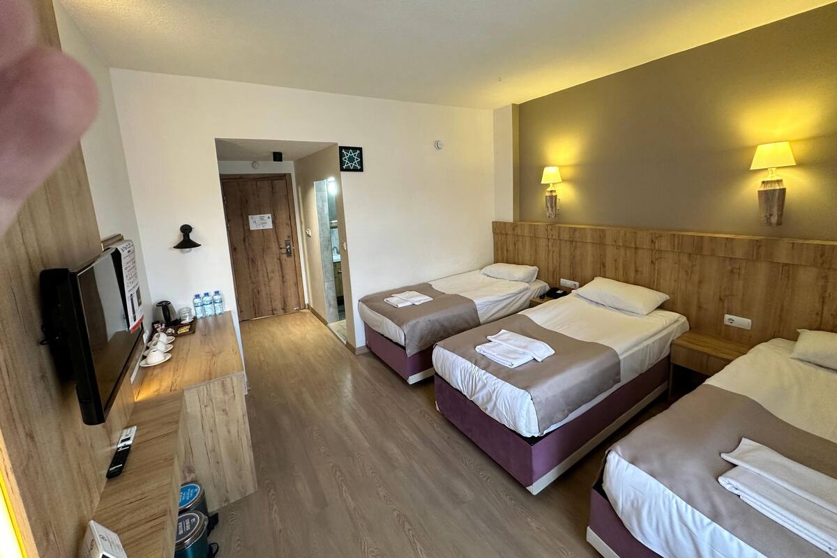 A hotel room with two beds, a TV, a desk with a lamp, and a bathroom visible through an open door.