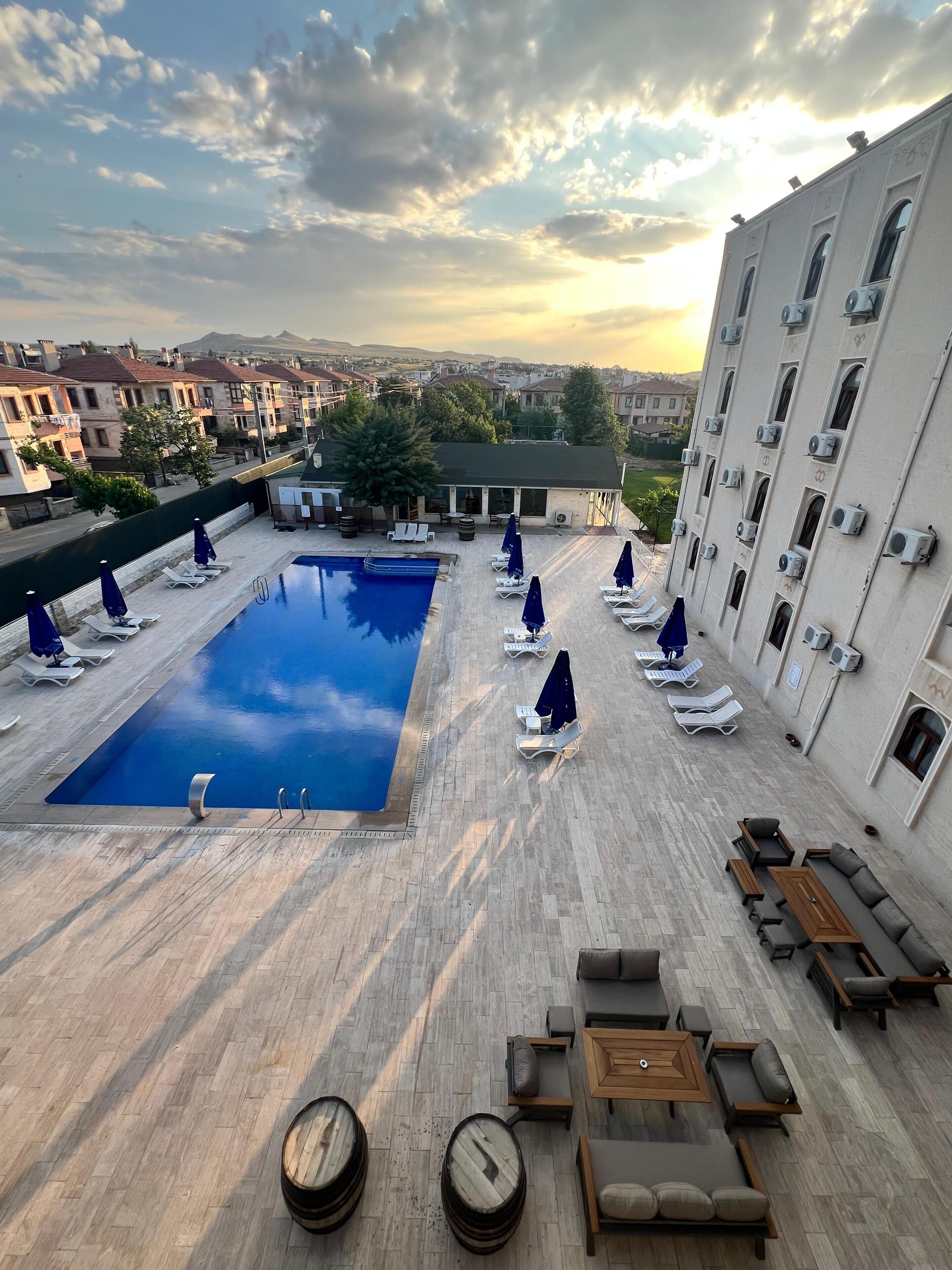 A rooftop pool area with lounge chairs, umbrellas, and a view of the cityscape.