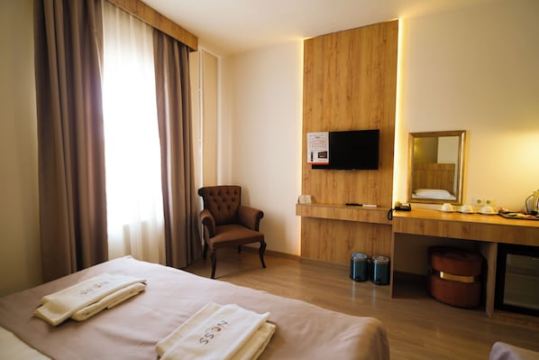 Una habitación de hotel con cama, una silla, escritorio, televisor y espejo.