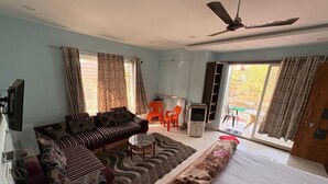 Una habitación con cama, sofá, una mesita y ventilador de techo.