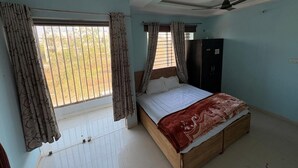 Un dormitorio con cama, cortinas, armario y ventilador de techo.