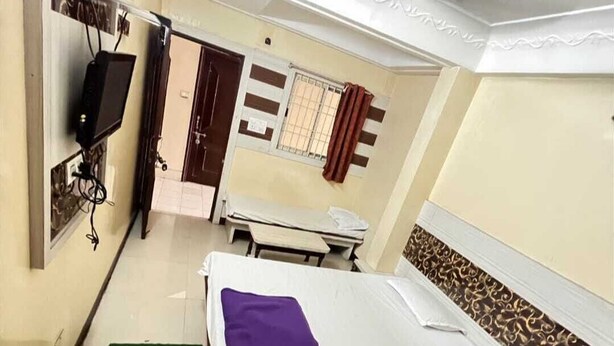 Una habitación de hotel con cama, televisor, ventana con cortinas y ventilador de techo.