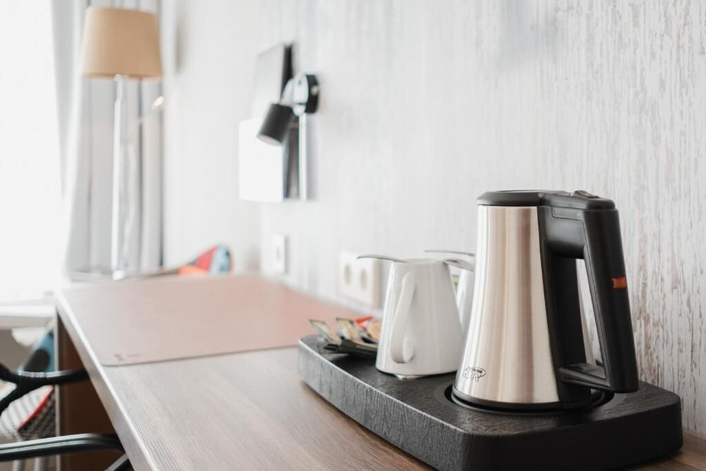 A modern kitchen with a coffee maker, kettle, and a tray with cards on a wooden table.