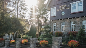 A stone building with a sign reading 'HOTEL HASSELHOF' and a stone fence with flower boxes. - Hotel Hasselhof Garni 4 Sterne (Braunlage)