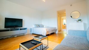 A modern living room with a flat-screen TV, a bed, a sofa, and a small table with a remote control. - Central Studio, Near City & Tram | Brämaregården (Gothenburg)