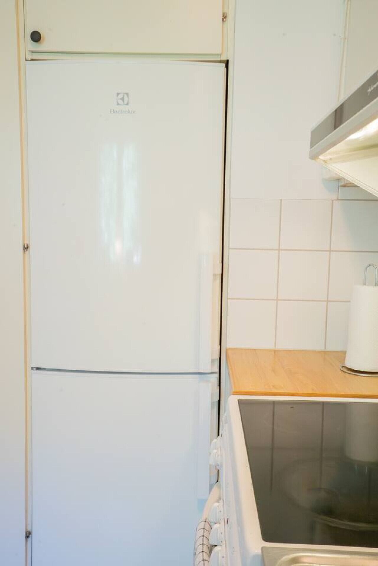 Une cuisine avec un réfrigérateur blanc, un plan de travail en bois et une cuisinière.
