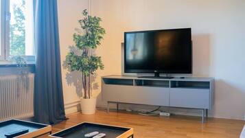Una sala de estar moderna con un televisor de pantalla plana, un sofá, una mesa de centro y una planta en maceta.