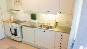 A kitchen with white cabinets, a stove, a sink, and a window. - Central Studio, Near City & Tram | Brämaregården (Gothenburg)