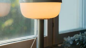 Una lampada moderna su un davanzale con vista su piante e spazi verdi.